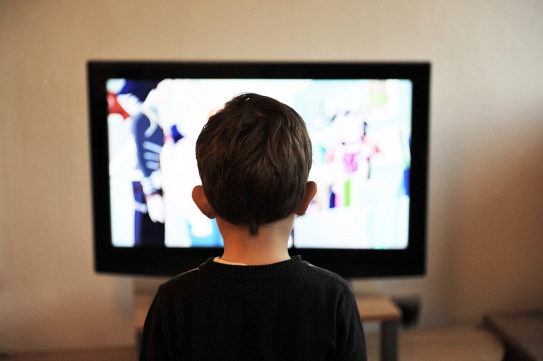 Niño frente a una pantalla de televisión