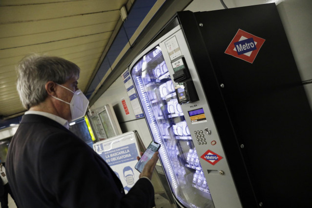 El consejero de Transportes, Ángel Garrido, utiliza una de las nuevas máquinas de 'vending' de mascarillas e hidrogel del Metro de Madrid en el marco de su presentación, donde le acompaña el vicepresidente, consejero de Deportes, Transparencia y portavoz