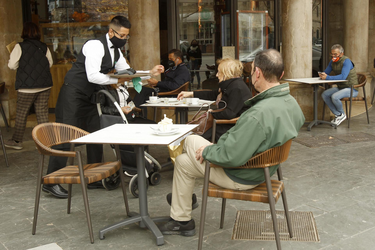 Un camarero atiende a varios clientes en la terraza de un bar en Palma, Mallorca, Islas Baleares (España),