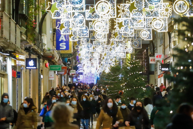 Archivo - Varias personas pasean por calles comerciales en Navidad
