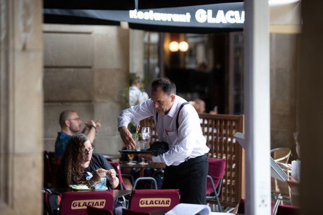 Archivo - Un camarero limpiando una mesa en un restaurante de Barcelona