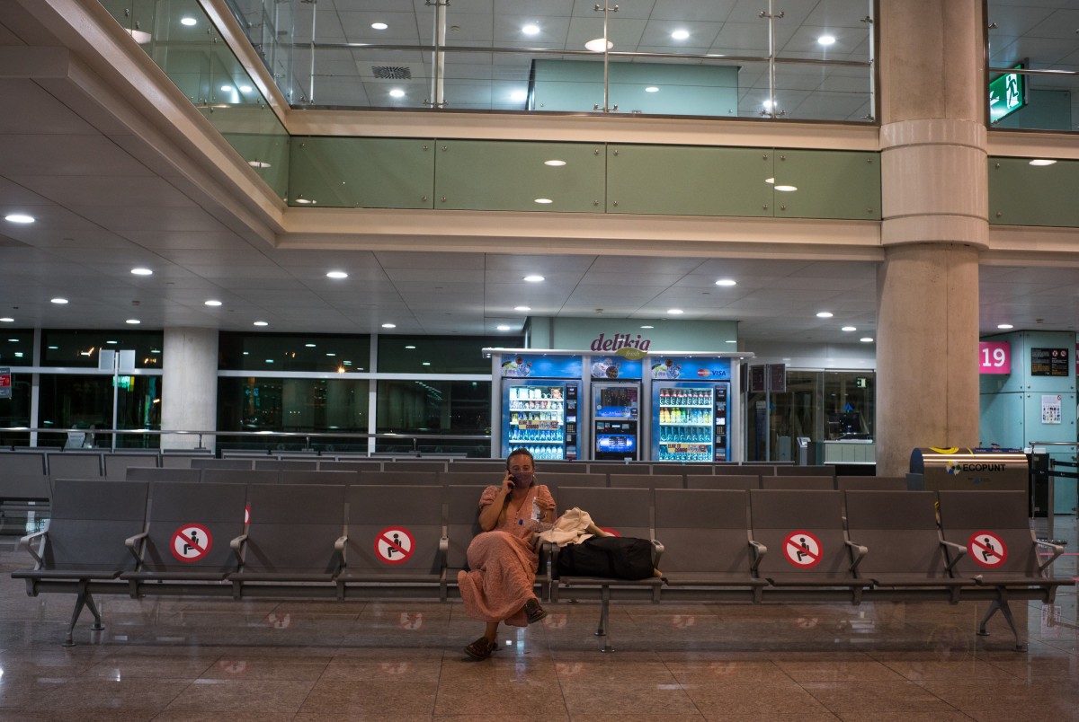 Una mujer espera sentada en unos asientos habilitados para preservar la distancia de seguridad en el Aeropuerto Josep Tarradellas Barcelona-El Prat, en Barcelona, Catalunya, (España), a 12 de septiem