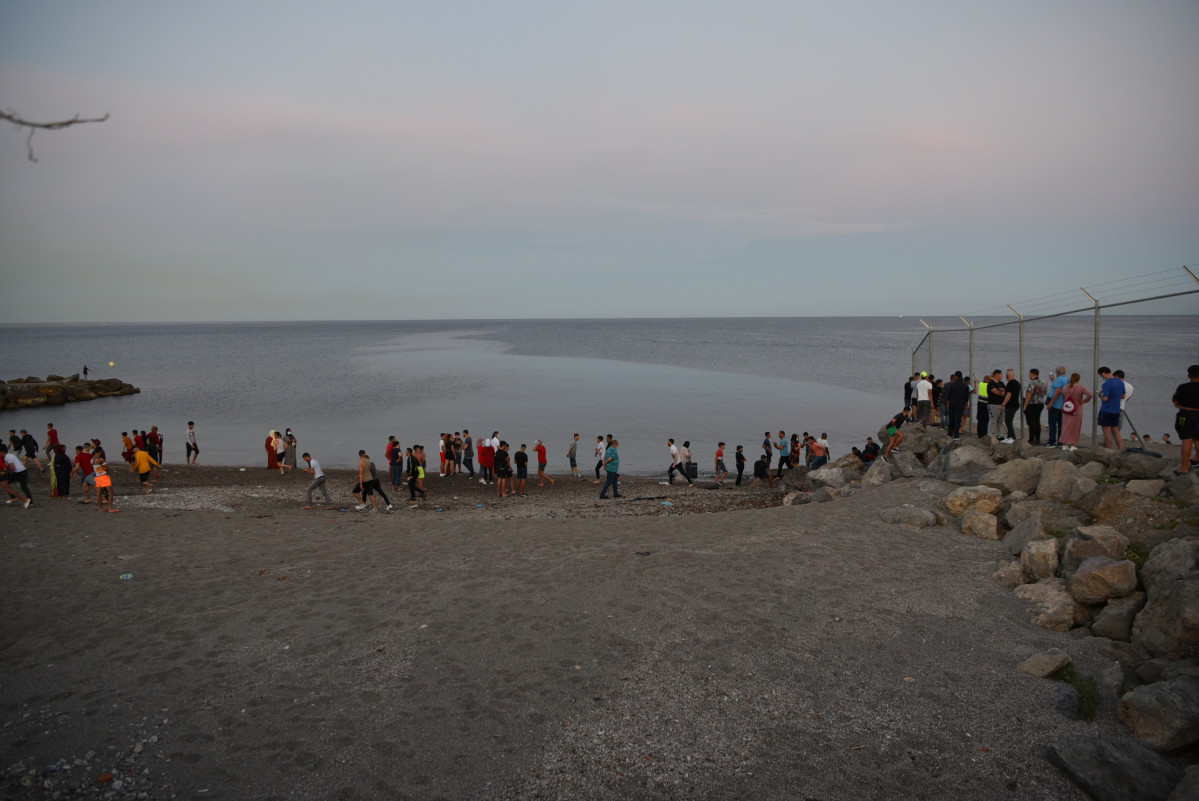 Personas migrantes caminan por la playa del Tarajal, a 17 de mayo de 2021, en Ceuta (España). España ha movilizado al Ejército en la ciudad tras la entrada de más de 5.000 marroquíes en 24 horas.
