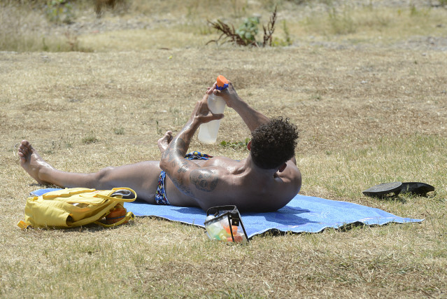 Un hombre toma el sol en la zona piscinas de Oira, a 12 de julio de 2022, en Orense, Galicia (España). Los termómetros de la práctica totalidad del territorio gallego alcanzarán valores “extremos” debido a la ola de calor que comenzó la semana pasada y qu