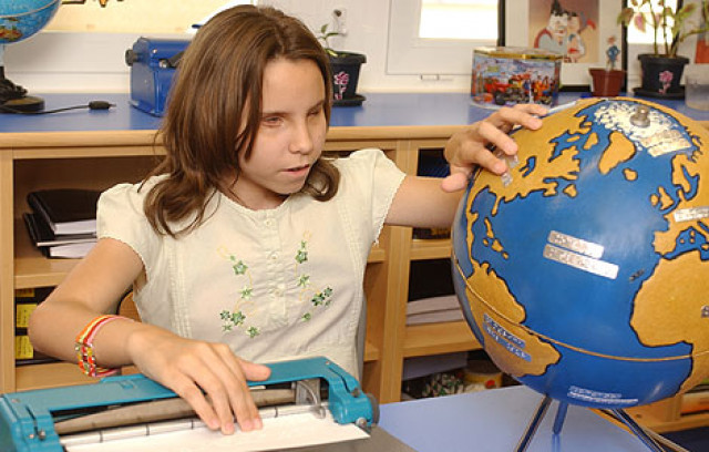 Una niña ciega estudia con un globo terráqueo 