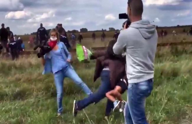 Periodista húngara en el momento en el que le pone la zancadilla a un refugiado sirio 