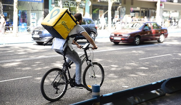 Trabajador de la empresa Glovo montando en bicicleta por Madrid