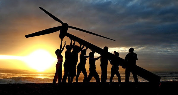 Greenpeace and Tcktcktck volunteers raise a wind turbine on the beach at dawn in