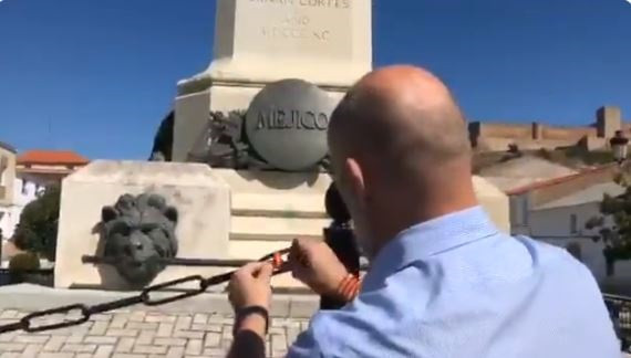 Miembros de VOX anudan una pulsera de España en la reja de la estatua de Hernán