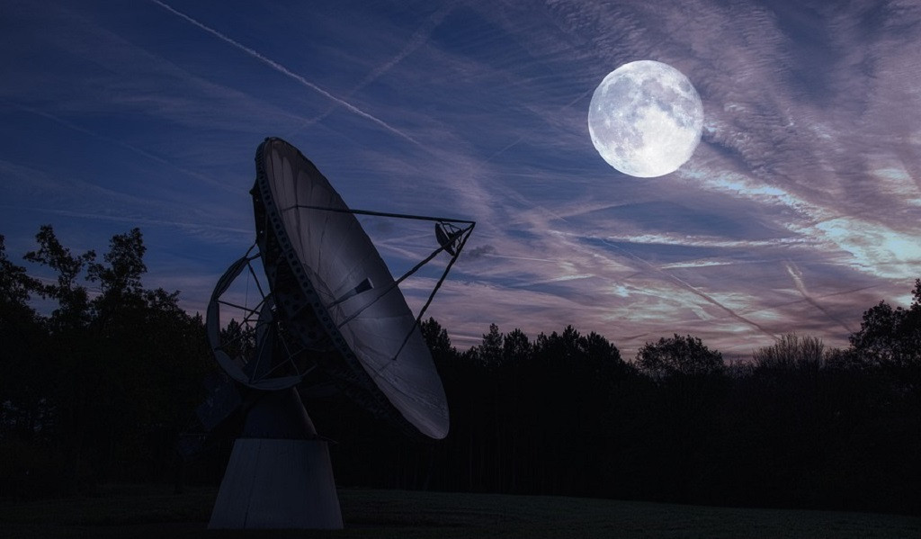 Radiotelescopio con la luna llena de fondo