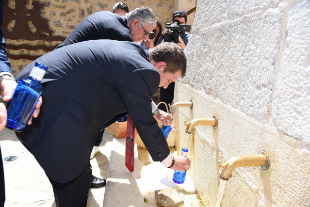 El presidente de C-LM, Emiliano García-Page, llena una botella de agua en la inauguración de 'Los baños de la reina' de Beteta (Cuenca).