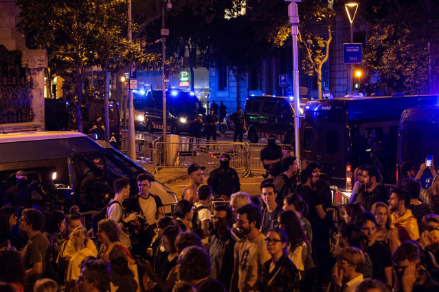 Participantes en la manifestación de la ANC junto a agentes y furgones de la Policía Nacional portan esteladas, en Barcelona a 1 de octubre de 2019.