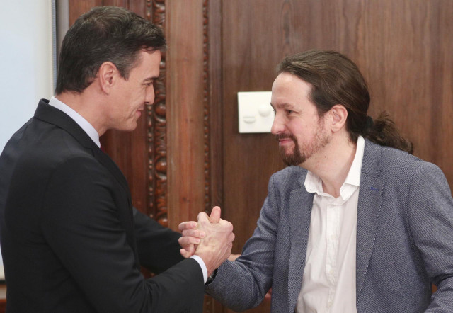El presidente del Gobierno en funciones, Pedro Sánchez, y el secretario general de Podemos, Pablo Iglesias, se saludan tras presentar su acuerdo de gobierno en el Congreso de los Diputados.