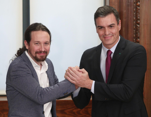 El presidente del Gobierno en funciones, Pedro Sánchez (dech.) y el secretario general de Podemos, Pablo Iglesias (izq), se dan la mano durante el acto de presentación del programa de Gobierno del PSOE y Unidas Podemos, en el Congreso de los Diputados, Ma