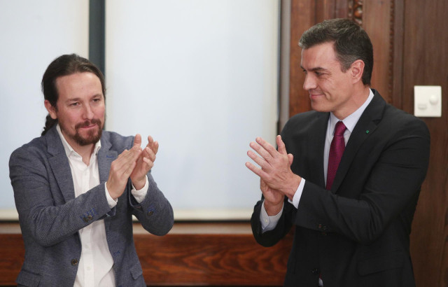 El presidente del Gobierno en funciones, Pedro Sánchez (dech) y el secretario general de Podemos, Pablo Iglesias (izq), aplauden durante el acto de presentación del programa de Gobierno del PSOE y Unidas Podemos