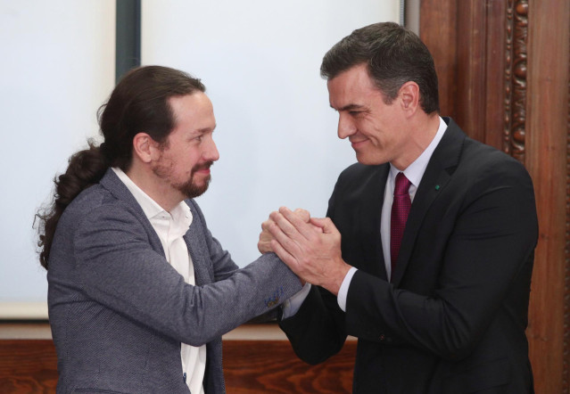 El presidente del Gobierno en funciones, Pedro Sánchez (dech.) y el secretario general de Podemos, Pablo Iglesias (izq), se dan la mano en la presentación del programa de Gobierno del PSOE y Unidas Podemos, en el Congreso de los Diputados