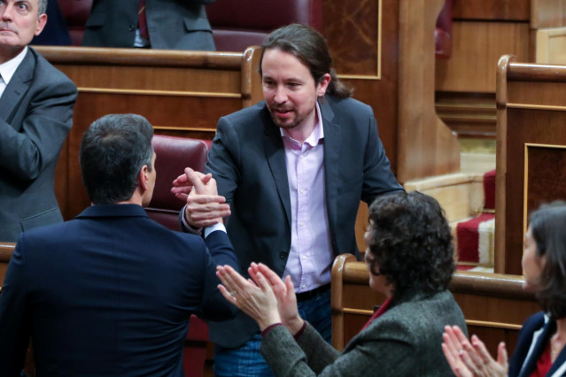 El líder de Podemos, Pablo Iglesias, estrecha la mano del presidente del Gobierno en funciones, Pedro Sánchez, tras su intervención en la primera sesión del debate de investidura de Sánchez en la XIV Legislatura en Madrid (España), a 4 de enero de 2020.