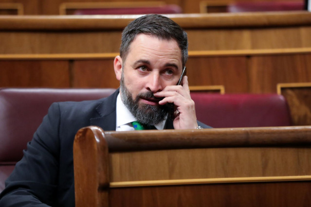 El presidente de VOX, Santiago Abascal, habla por teléfono desde su escaño.