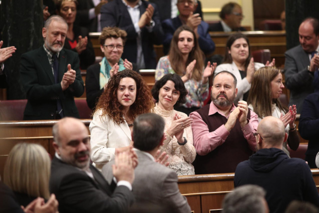 La diputada de Unidas Podemos, Aina Vidal (con chaqueta blanca), se emociona al recibir el aplauso de su bancada junto a la socialista, tras el agradecimiento que le ha expresado Pablo Iglesias por haber asistido a la votación a pesar de estar enferma.
