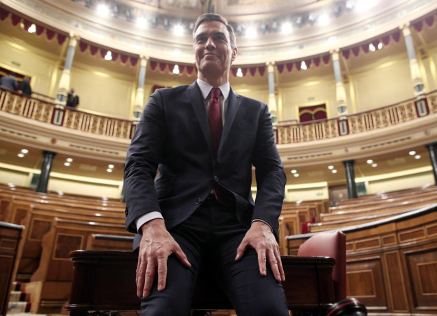 El presidente del Gobierno, Pedro Sánchez, posa sonriente en el hemiciclo del Congreso de los Diputados, tras obtener una votación favorable a su investidura (de 167 a 165 y 18 abstenciones)