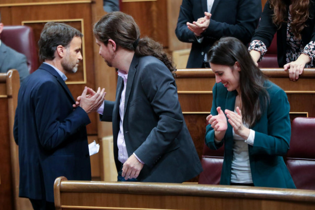 El secretario general de Podemos, Pablo Iglesias (c), estrecha la mano del  portavoz parlamentario de En Comú (ECP), Jaume Asens, tras su intervención en la primera sesión del debate de investidura del candidato socialista a la Presidencia de Gobierno en