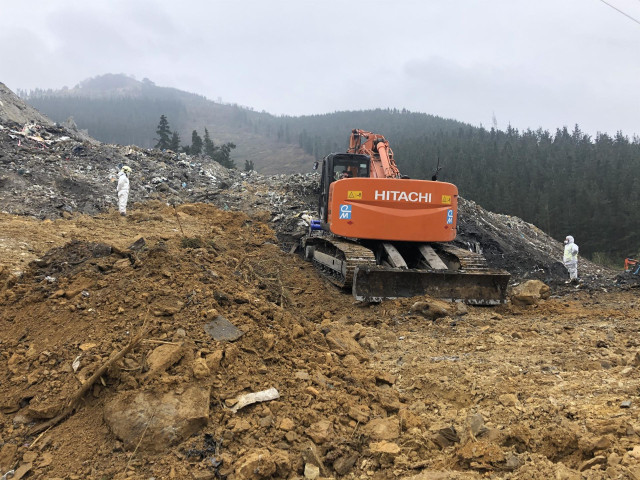 Imagen de la pala excavadora y de dos operarios supervisando los trabajos en el vertedero de Zaldibar.