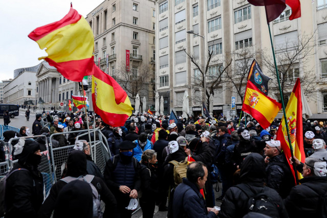 Manifestantes con máscaras de Anonymous y banderas de España se concentran frente a las puertas del Congreso de los Diputados en rechazo al veto del Gobierno al debate de la Iniciativa Legislativa Popular (ILP) presentada por Jusapol
