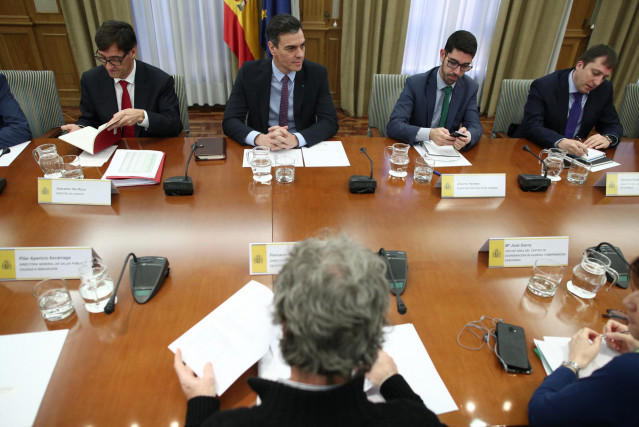 El ministro de Sanidad, Salvador Illa (1i), habla con el presidente del Gobierno, Pedro Sánchez (2i), acompañados del director del Centro de Coordinación de Alertas y Emergencias Sanitarias del Ministerio de Sanidad, Fernando Simón (frente a Sánchez), dur