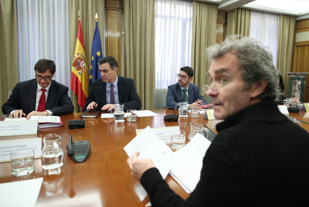 El ministro de Sanidad, Salvador Illa (1i), habla con el presidente del Gobierno, Pedro Sánchez (2i), acompañados del director del Centro de Coordinación de Alertas y Emergencias Sanitarias del Ministerio de Sanidad, Fernando Simón (frente a Sánchez