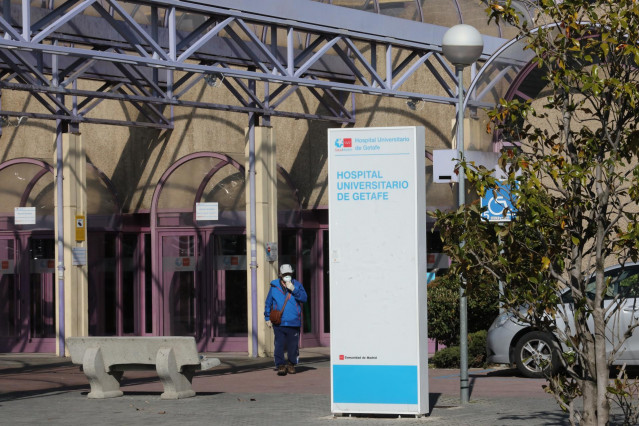 Un hombre pasea al lado de uno de los carteles indicativos del Hospital Universitario de Getafe cerca de la carpa de material donde las Fuerzas Armadas colocaron ayer material de apoyo con 2 grupos electrógenos.