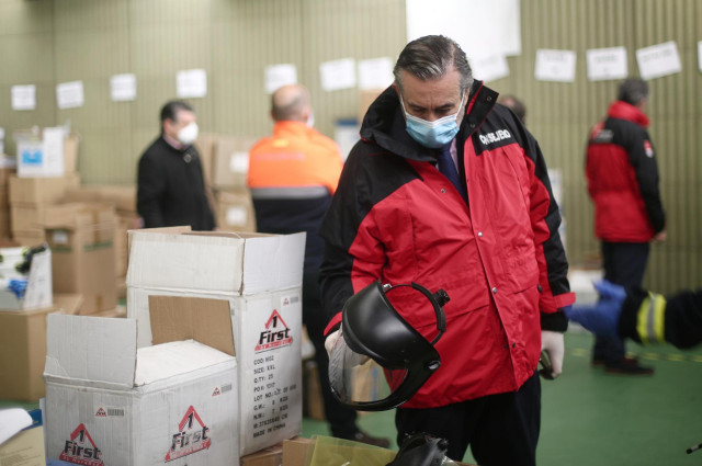 El consejero de Justicia de la Comunidad de Madrid, Enrique López, protegido con una mascarilla, sujeta una pantalla de protección durante su visita al centro logístico de la Comunidad de Madrid en el que se recogen las donaciones de material sanitario pa