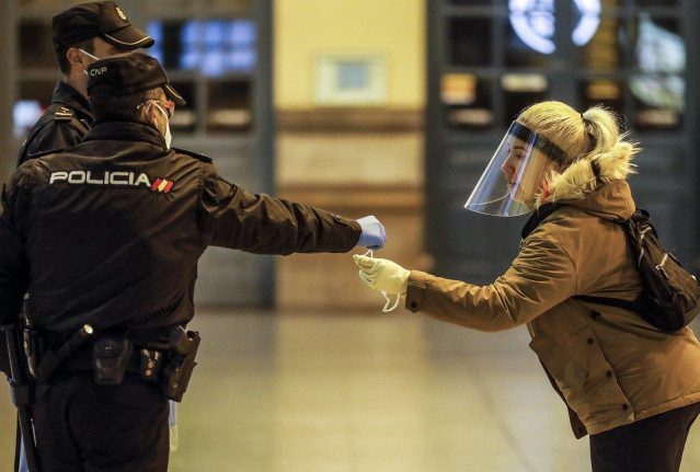 Un agente de Policía Nacional entrega una mascarilla en el vestíbulo de la estación Norte de Valencia