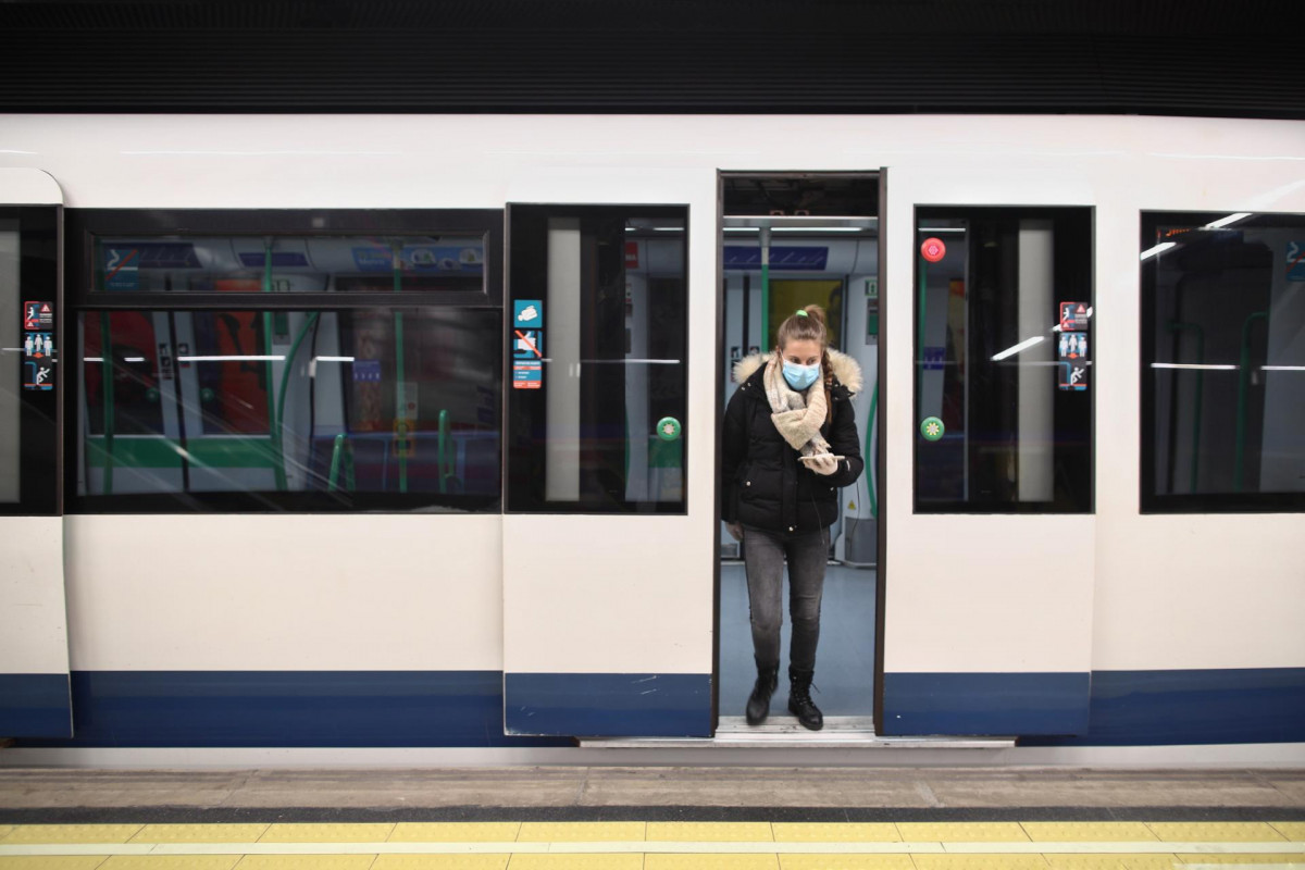 Una mujer protegida con mascarilla se baja de uno de los metros de la capital en un andén con círculos rojos en el suelo que Metro de Madrid ha colocado en sus estaciones para establecer distancia d