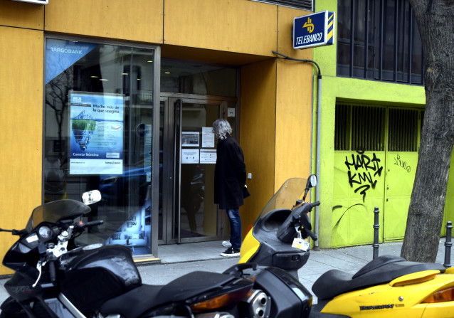 Un hombre lee en un cartel las directrices de una oficina Targo Bank