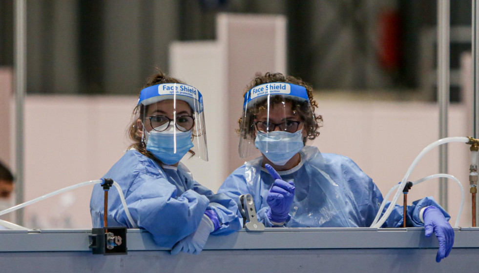 Dos sanitarias protegidas con mascarilla, guantes y pantalla protectora.