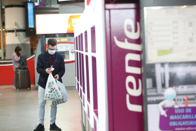 Un viajero con mascarilla obtiene un billete en un dispensador en la estación de Atocha