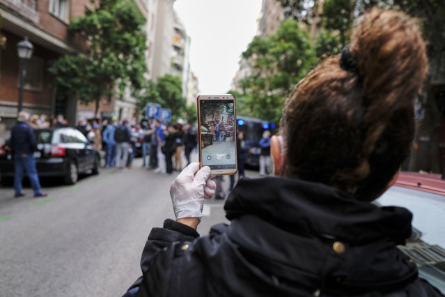 Una mujer hace una fotografía con su móvil en la concentración de protesta contra Sánchez en la calle Núñez de Balboa de Madrid.