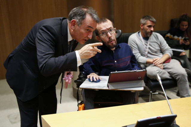 El portavoz de Unidas Podemos Pablo Echenique (d) y el diputado de esta formación Enrique Santiago (i), conversan en el Congreso