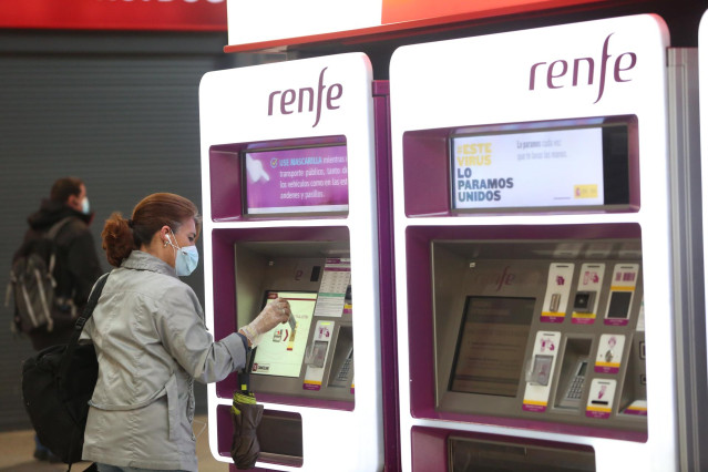 Una viajera con mascarilla adquiere un billete en un dispensador en la estación de Atocha.