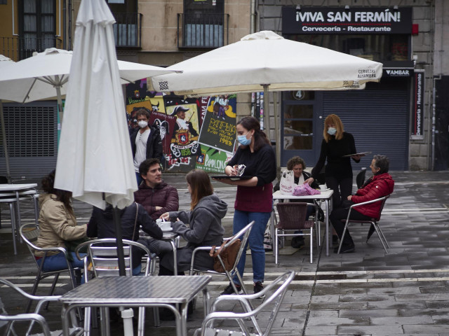 Una camarera atiende a varias personas sentadas en una terraza de Navarra