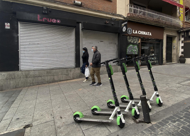 Dos personas protegidas con mascarillas caminan por una calle del madrileño barrio de Chueca