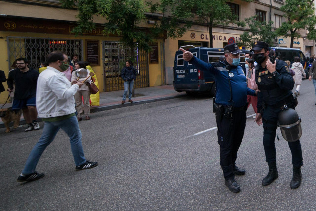 Un agente de Policía Municipal hace indicaciones a uno de Policía Nacional en una protesta en la sede del PSOE en Madrid