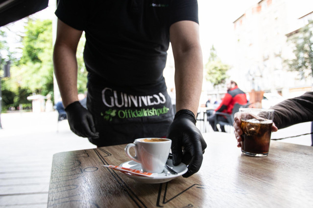 Un camarero sirve un café en una terraza en el centro de Vitoria (Álava)