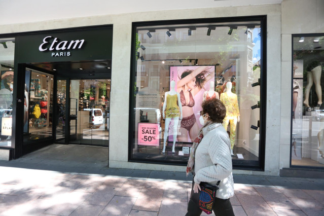 Una mujer pasa junto a una tienda Etam en la que se anuncian rebajas de hasta  el 50% el día en el que el Gobierno permite finalmente las rebajas desde hoy en toda España siempre que no generen aglomeraciones, en Madrid (España) a 18 de mayo de 2020.