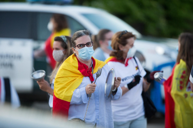 Varias personas golpean cacerolas en señal de protesta con banderas de España por las inmediaciones del cordón establecido por la Guardia Civil en un perímetro de varias manzanas alrededor de la vivienda del vicepresidente del Gobierno de España, Pablo Ig