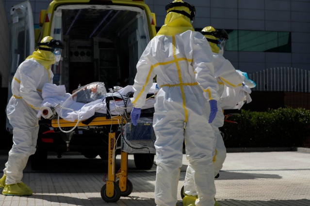 Varios sanitarios trasladan a un paciente desde el interior de la unidad móvil del SUMMA hasta la entrada del Hospital Puerta de Hierro con equipos de protección individual (EPI).