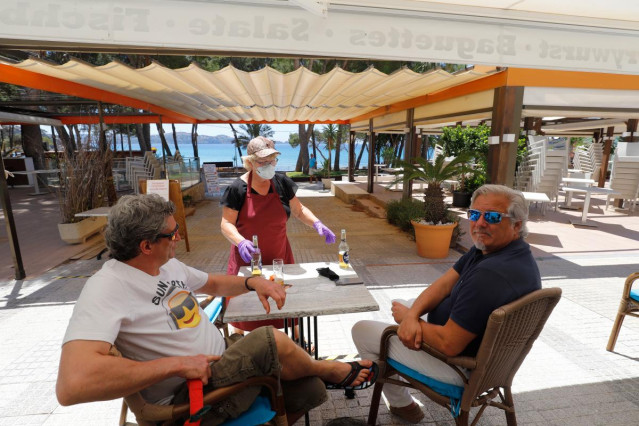 20 May 2020, Spain, Calvia: A waitress serves beer to customers at the 