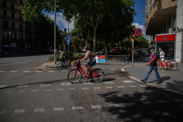 Transeúentes pasan al lado de las vallas instaladas para cortar el tráfico lateral de la Diagonal (Diagonal-Sant En Barcelona, Catalunya (España), a 13 de mayo de 2020.