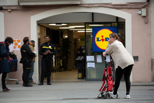 Una mujer espera con su carro de la compra a poder entrar a un supermercado Lidl