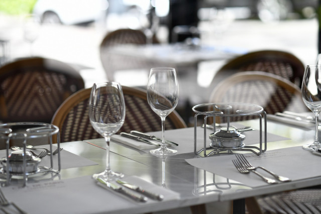Una mesa en una terraza con unos hornillos, copas de vino y cubiertos.